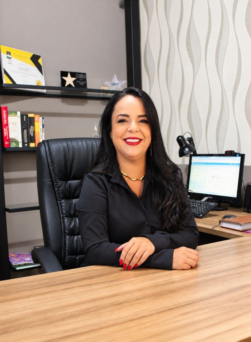 Retrato profissional de advogada sentada à mesa do escritório