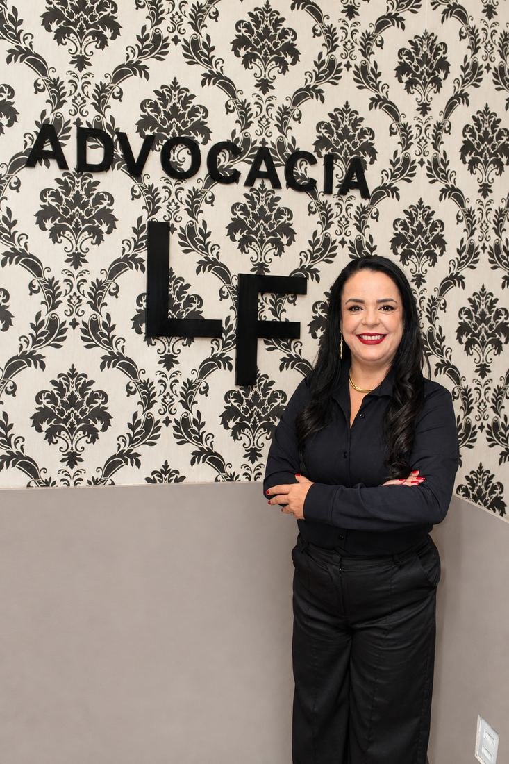 Retrato profissional de advogada diante da parede com o logotipo do escritório