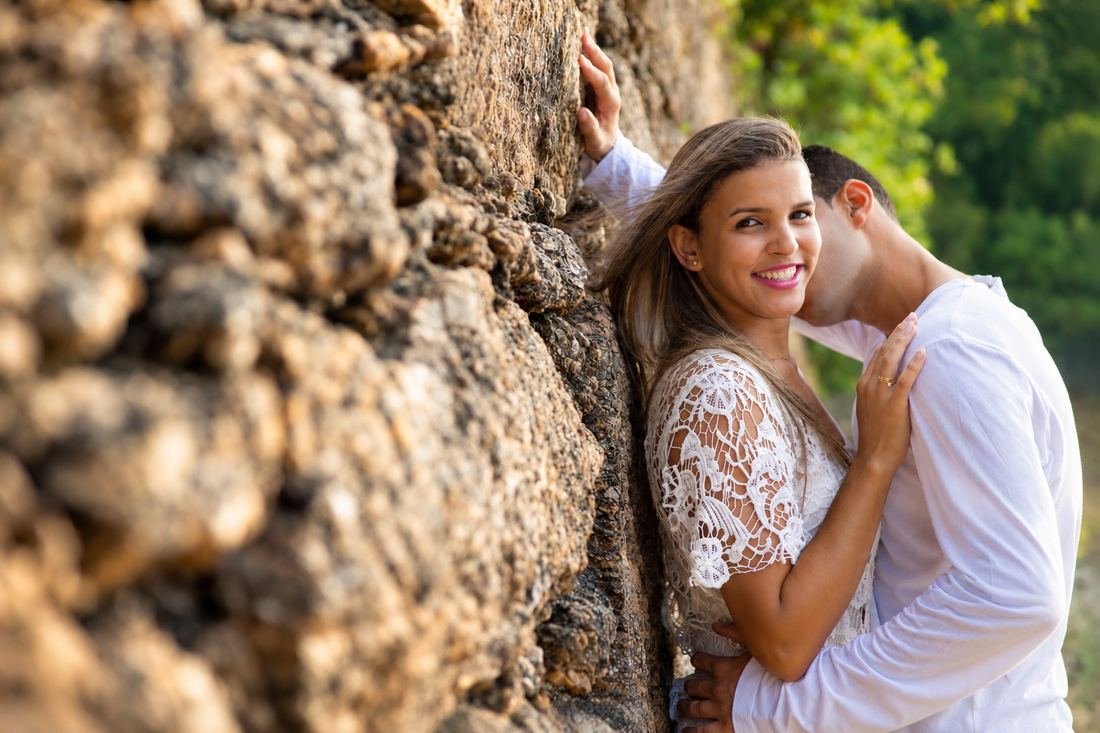 Ensaio de casal abraçado junto a um muro de pedra